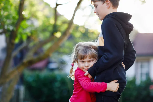 Söt liten flicka kramar äldre bror. Förtjusande glad barn kramar pojke. Syskon i kärlek, familj och gemenskap. — Stockfoto