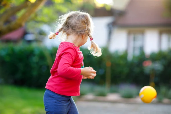 Liten bedårande liten flicka leker med bollen utomhus. Glad leende barn fånga och kasta, skrattar och göra sport. Aktiv fritid med barn och barn. — Stockfoto