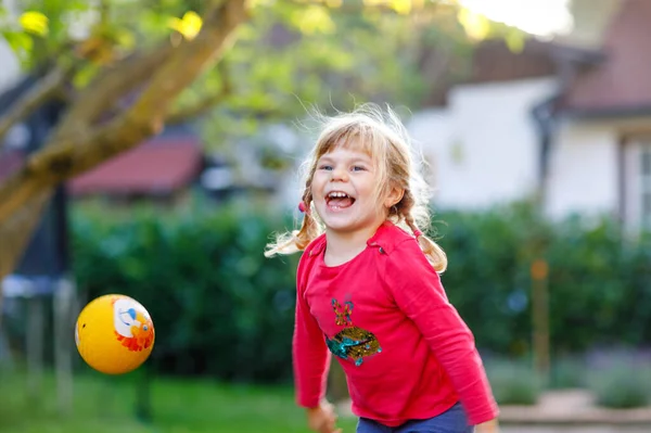 Liten bedårande liten flicka leker med bollen utomhus. Glad leende barn fånga och kasta, skrattar och göra sport. Aktiv fritid med barn och barn. — Stockfoto