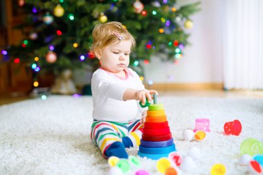 Evde ya da çocuk odasında eğitici oyuncaklarla oynayan sevimli, güzel bir kız bebek. Mutlu sağlıklı çocuk renkli ahşap çocuk oyuncak piramidiyle eğleniyor. Çocuk farklı yetenekler öğreniyor.