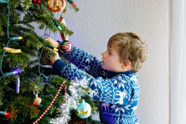 Küçük çocuk Noel ağacından Noel süslerini indiriyor. Kutlamalardan sonra aile ağacı kaldırır ve imha eder. Ren geyikleriyle şenlikli kıyafetler giyen çocuklar..
