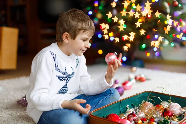 Schöner Junge und bunte Vintage-Weihnachtsspielzeuge und -Bälle. Kind schmückt Weihnachtsbaum — Stockfoto