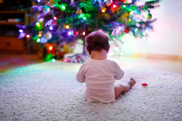 Roztomilé holčička drží barevné světla girland v roztomilých rukou. Malé dítě ve slavnostním oblečení zdobí vánoční stromeček s rodinou. První oslava tradičního svátku Weihnachten — Stock fotografie