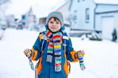 Mutlu çocuk okula giderken karla eğleniyor.