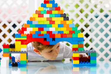 Küçük sarışın çocuk ve çocuk bir sürü renkli plastik blokla oynuyorlar..