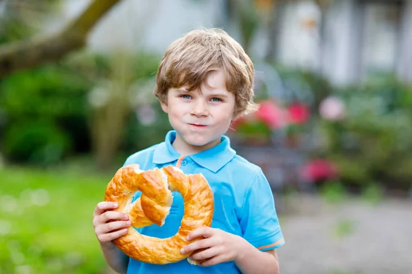 Adorabile bambino ragazzo mangiare enorme grande bavarese tedesco pretzel. — Foto Stock