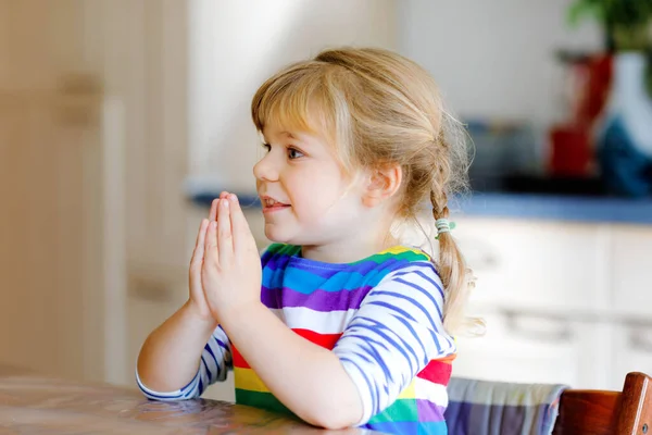 Linda niña rezando a Dios en casa. Niño usando las manos para orar y gracias por la comida. Tradición cristiana. —  Fotos de Stock