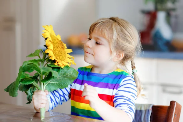 Entzückendes Kleinkind Mädchen und Sonnenblume. Nettes Kind mit großer blühender Blume. — Stockfoto