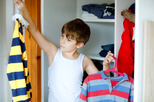 小学生穿着衣服站在衣橱旁.孩子们决定穿校服.孩子们早上穿好衣服去上学. — 图库照片