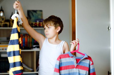 Okullu çocuk kıyafetlerle gardıropta bekliyor. Çocuk okul gömleği giymeye karar veriyor. Çocuklar sabah okula gitmek için giyinirler..