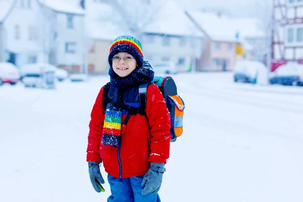 Dos niños pequeños de la clase primaria caminando a la escuela durante las nevadas —  Fotos de Stock