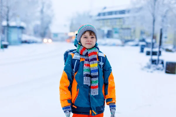 Niño feliz divirtiéndose con nieve camino a la escuela — Foto de Stock