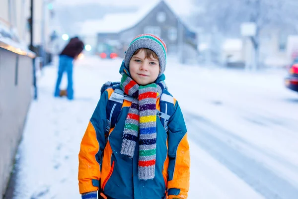 Счастливый мальчик веселится со снегом по дороге в школу — стоковое фото