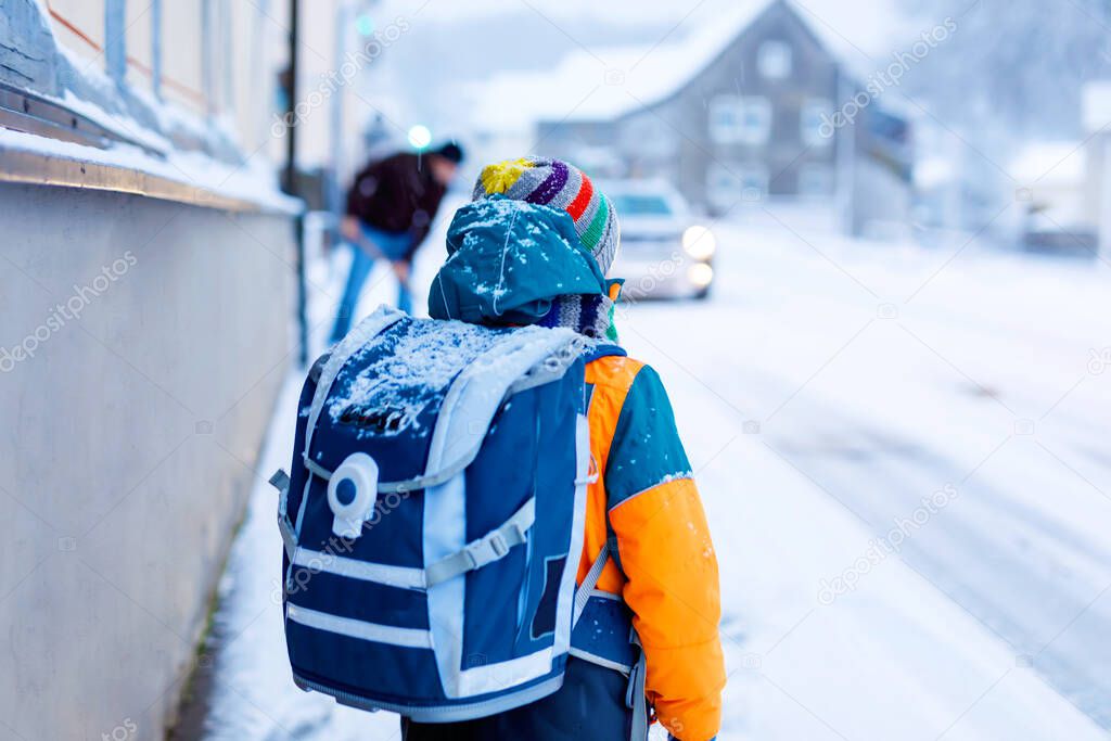 Happy kid boy having fun with snow on way to school