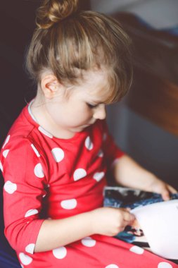 Moda dergisi ya da katalog okuyan küçük şık bir kız. Sevimli çocuk kıyafet seçerken eğleniyor..