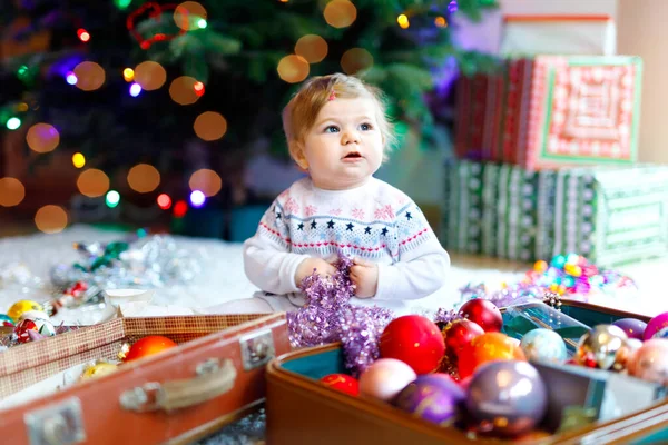 Söt liten flicka som håller färgglada ljus körtel i söta händer. Små barn i festliga kläder dekorera julgran med familj. Första firandet av traditionell semester som heter Weihnachten — Stockfoto