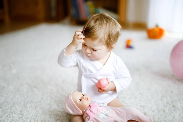 Preciosa linda y hermosa niña jugando con muñequita de juguete en casa o guardería. Feliz niño sano divirtiéndose con diferentes juguetes. Niños pequeños aprendiendo diferentes habilidades. —  Fotos de Stock