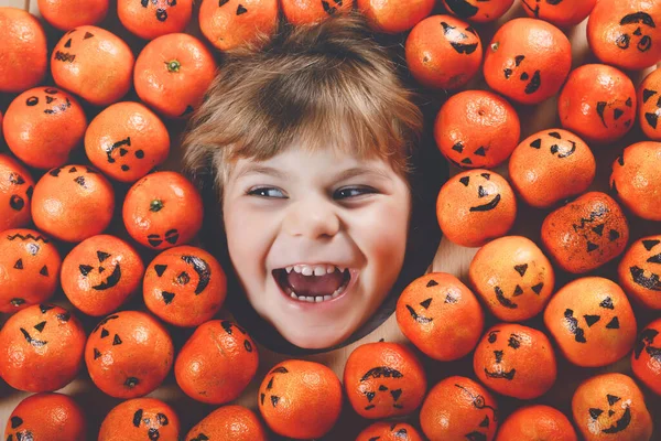 Забавный портрет очаровательной девочки-малышки с апельсиновым мандарином, выглядящей как маленькая тыква-фонарик. Счастливая улыбка ребенка праздник Хэллоуин фестиваль или вечеринка. Создание открыток для друзей. — стоковое фото