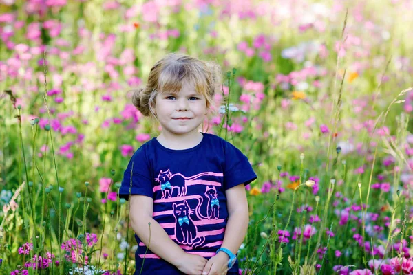 꽃 밭에 있는 사랑스럽고 매력적 인 걸음마하는 소녀의 이야기. 여름 날에는 화려 한 꽃을 활짝 핀 행복 한 아기를 야외에서 젖을 먹이는 것이다. 행복과 여름철. — 스톡 사진