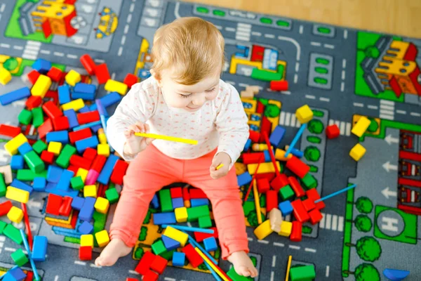 Eğitici oyuncaklarla oynayan sevimli bir kız bebek. Mutlu sağlıklı bir çocuk, evdeki renkli tahta bloklarla eğleniyor. Bebek öğrenme renkleri ve biçimleri — Stok fotoğraf