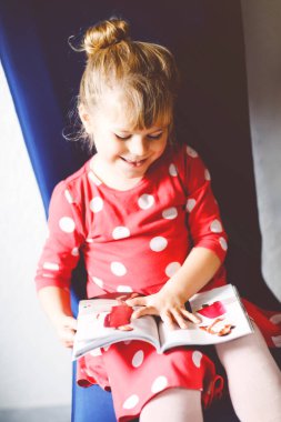 Moda dergisi ya da katalog okuyan küçük şık bir kız. Sevimli çocuk kıyafet seçerken eğleniyor..