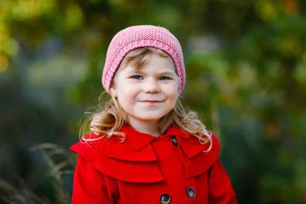 Menina pequena bonito em casaco vermelho fazendo um passeio através da floresta de outono. Bebê saudável feliz gostando de andar com os pais. Dia de outono ensolarado com criança. Lazer ativo e atividade com crianças na natureza. — Fotografia de Stock