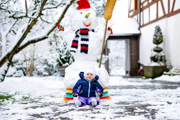 Kış günü kar ve kardan adamla küçük tatlı bir kız bebek. — Stok fotoğraf