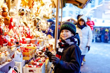 Noel pazarında dekorasyon seçen sevimli çocuk. Oyuncaklar için alışveriş yapan güzel bir çocuk ve ağaç için dekoratif süsler. Almanya 'da Xmas pazarı.