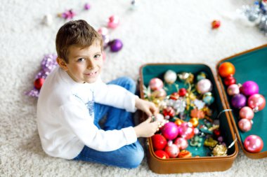 Güzel bir çocuk ve renkli eski bir Noel oyuncağı ve eski bir bavulda top. Çocuk Noel ağacı süslemesi