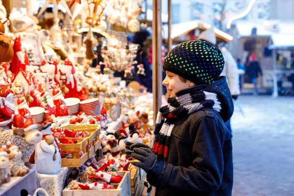 Pequeno garoto bonito menino selecionando decoração no mercado de Natal. Bonita criança compras de brinquedos e ornamentos decorativos coisas para a árvore. Mercado de Natal na Alemanha. — Fotografia de Stock