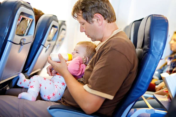Isä pitelee tytärtään lentokoneessa lomalla. — kuvapankkivalokuva