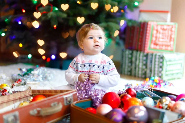 Adorable bébé fille tenant guirlande de lumières colorées dans des mains mignonnes. Petit enfant en vêtements de fête décorant l'arbre de Noël en famille. Première célébration de la fête traditionnelle appelée Weihnachten — Photo