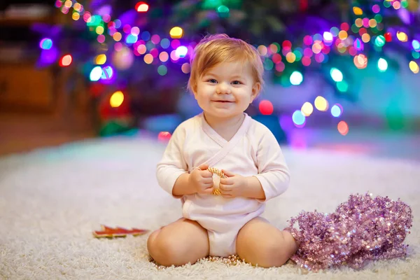 Adorable bébé fille tenant guirlande de lumières colorées dans des mains mignonnes. Petit enfant en vêtements de fête décorant l'arbre de Noël en famille. Première célébration de la fête traditionnelle appelée Weihnachten — Photo
