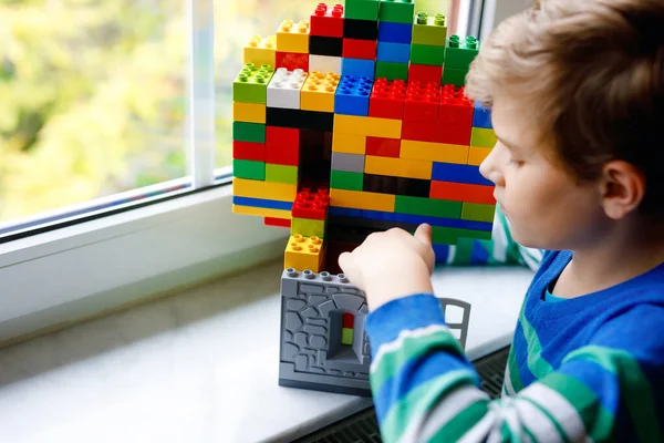 Menino brincando com muitos blocos de plástico coloridos. Criança adorável da escola se divertindo com a construção e criação de construção por janela. Técnico de lazer criativo e robótico durante o tempo corona — Fotografia de Stock