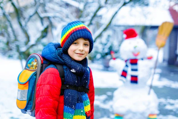 Lykkelig guttunge med briller som morer seg med snø på vei til skolen, grunnskole – stockfoto