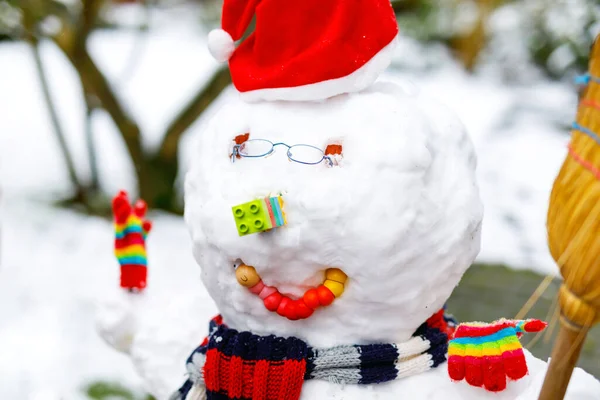 Little kid putting eye glasses on snowman. Close-up. child having fun with first snow in winter — Stock Photo, Image