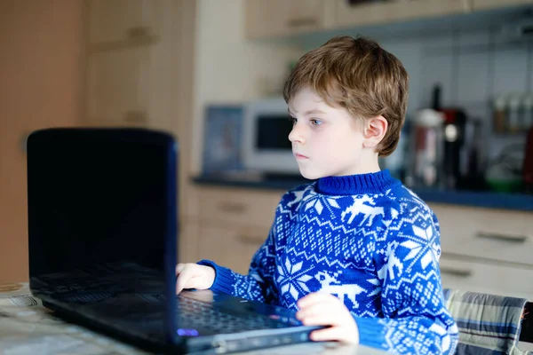 Lonely kid boy learning at home on laptop for school. Adorable child making homework and using notebook and modern gadgets. Home schooling concept during pandemic corona virus lockdown quarantine — Stock Photo, Image