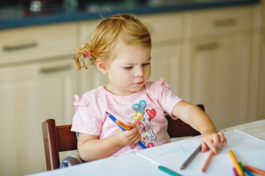 Kalemle resim yapmayı öğrenen sevimli bir bebek. Küçük çocuk renkli keçeli kalemlerle evde resim çiziyor. Evde ya da çocuk odasında renkler deneyen sağlıklı, mutlu bir kız.