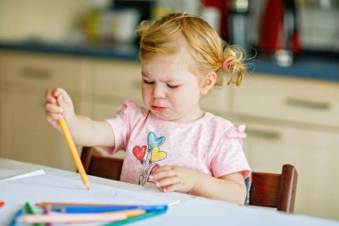 Kalemle resim yapmayı öğrenen sevimli bir bebek. Küçük çocuk renkli keçeli kalemlerle evde resim çiziyor. Evde ya da çocuk odasında renkler deneyen sağlıklı, mutlu bir kız.