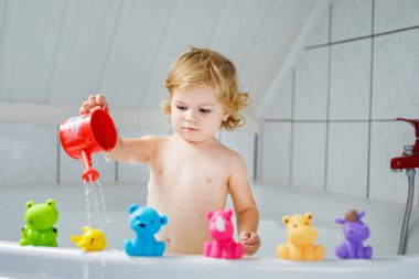 Çok sevimli şirin küçük yürümeye başlayan çocuk kız alma banyo küvet içinde. Kauçuk sakız oyuncaklar ile oynama ve eğlenerek mutlu sağlıklı bebek çocuk. Yıkama, temizlik, hijyen çocuklar için