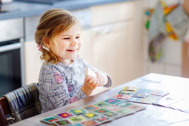 Heyecanlı, gülümseyen küçük kız iskambil oynuyor. Mutlu sağlıklı çocuk hafızasını eğitiyor, düşünüyor. Çocuk için evde yaratıcı bir eğlence ve eğitim. Evde aile aktivitesi