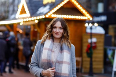 Güzel genç bir kadın, şiddetli kar yağışında geleneksel Noel pazarında eğleniyor. Mutlu kız Almanya 'da geleneksel aile pazarının tadını çıkarıyor. Aydınlanmış Xmas 'ın yanında duran kadın