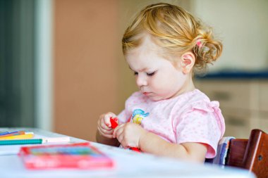 Kalemle resim yapmayı öğrenen sevimli bir bebek. Küçük çocuk renkli keçeli kalemlerle evde resim çiziyor. Evde ya da çocuk odasında renkler deneyen sağlıklı, mutlu bir kız.