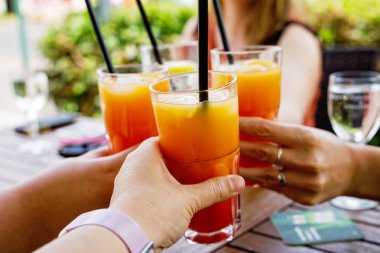 İnsanlar bardakları kokteyl, aperol ve şarapla dolduruyor. Kadın arkadaşlar yaz günü birlikte eğleniyorlar.