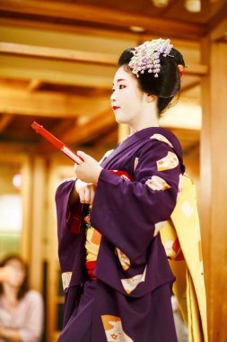 KYOTO, JAPONYA - 18 Mayıs 2015: Japon geleneksel dansını gösteren Maiko çırağı. Maiko bir çırak geyşa. Maikos ozashiki 'deki ziyaretçiler için şarkı söylüyor, shamisen çalıyor veya enstrümanlar çalıyor