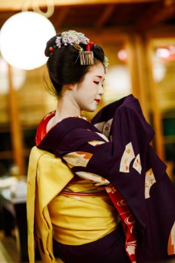 KYOTO, JAPONYA - 18 Mayıs 2015: Japon geleneksel dansını gösteren Maiko çırağı. Maiko bir çırak geyşa. Maikos ozashiki 'deki ziyaretçiler için şarkı söylüyor, shamisen çalıyor veya enstrümanlar çalıyor
