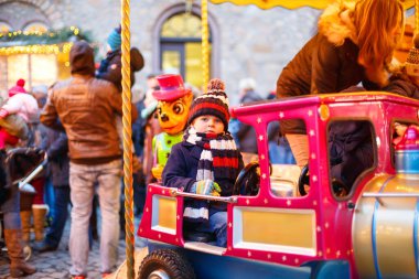 Komik küçük çocuk çocuk Noel lunapark veya Pazar, açık havada bir atlıkarınca üstünde. Mutlu çocuk eğleniyor. Almanya, Europe geleneksel Noel Pazar. Tatil, çocuklar, yaşam tarzı konsepti.