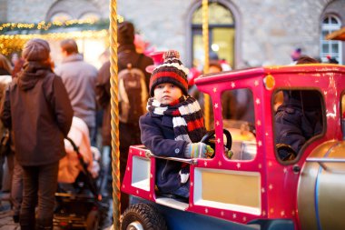 Komik küçük çocuk çocuk Noel lunapark veya Pazar, açık havada bir atlıkarınca üstünde. Mutlu çocuk eğleniyor. Almanya, Europe geleneksel Noel Pazar. Tatil, çocuklar, yaşam tarzı konsepti.