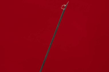 Düşürmeli şırınganın hipodermik iğnesi, kırmızı arka planda izole edilmiş yakın plan.