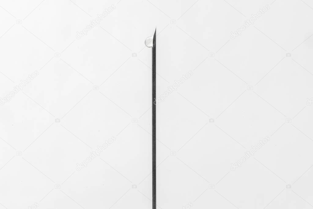 Hypodermic needle of a syringe with a drop, closeup isolated on white background
